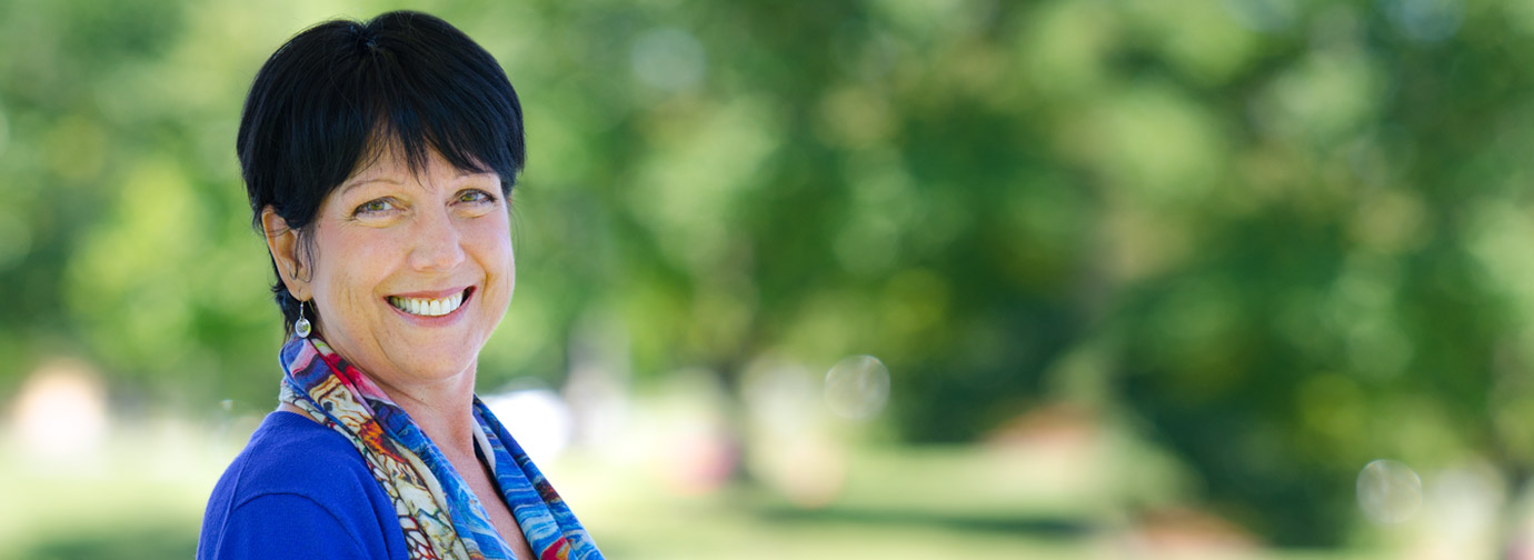 Dark haired woman in blue with paisley scarf smiling at camera