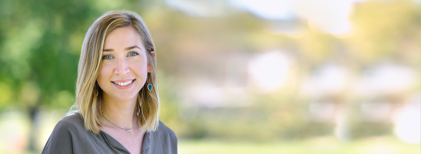 Blonde woman with gray shirt smiling at camera