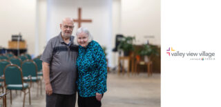 Dick and Erma Dell Jensen, pictured at Valley View Village chapel in Des Moines IA, smile together, where they enjoy gatherings and recently supported renovations to improve the space.